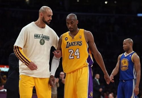 Kobe Bryant (R) of the Los Angeles Lakers is helped off the court by teammate Robert Sacre, April 12, 2013