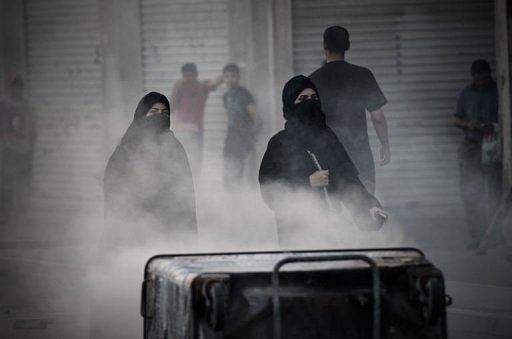 Bahraini women walk behind rubbish containers, used by anti-government protestors in Jidhafs on April 15, 2013
