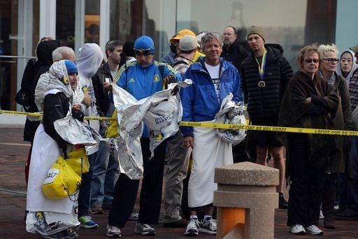 Runners listen to directions from police after two explosive devices detonated at the Boston Marathon on April 15, 2013
