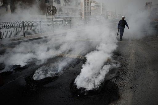 A Bahraini policeman walks past tyres burning during clashes between riot police and protesters in Diraz, April 18, 2013