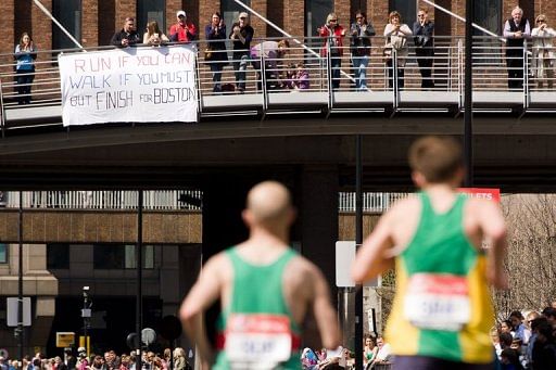 Runners pass beneath a bridge where spectators display a banner showing support for Boston in London on April 21, 2013