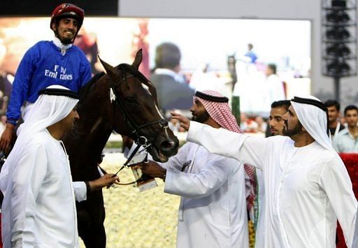 Dubai ruler Sheikh Mohammed bin Rashed Al Maktoum (R) pets a horse after it won the Godolphin Mile on March 27, 2010