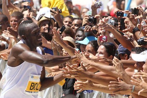 Jamaican runner Usain Bolt greets the public at the end of a race at Copacabana Beach on March 31, 2013