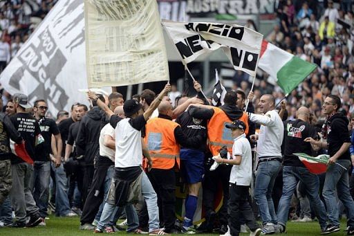 Juventus&#039; supporters stand on the pitch after their team defeated Palermo to win the Scudetto on May 5, 2013 in Turin