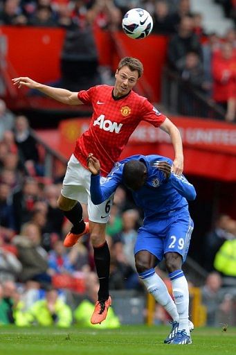 Chelsea&#039;s Demba Ba (R) ducks as Manchester United defender Jonny Evans makes an acrobatic clearance  on May 5, 2013