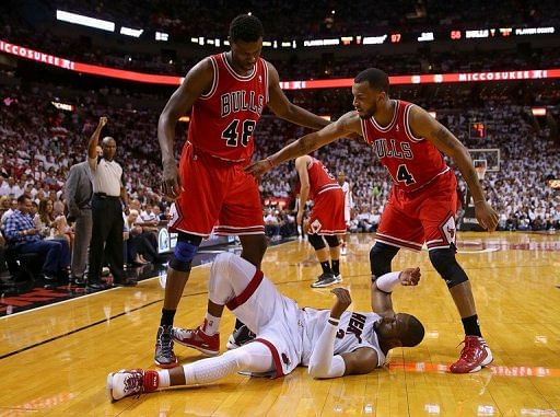 Dwyane Wade of the Miami Heat is knocked down by Nazr Mohammed (L) and Daequan Cook of the Chicago Bulls on May 8, 2013