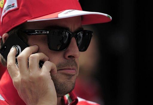 Fernando Alonso talks on a phone in the paddock at the Circuit de Catalunya in Montmelo near Barcelona on May 9, 2013