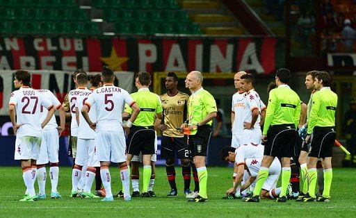 AS Roma players stand on the field after Italian referee Gianluca Rocchi suspended the match on May 12, 2013