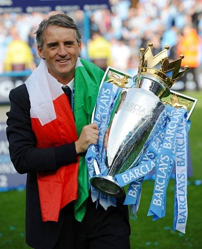 Roberto Mancini celebrates with the Premier League trophy at The Etihad stadium in Manchester on May 13, 2012
