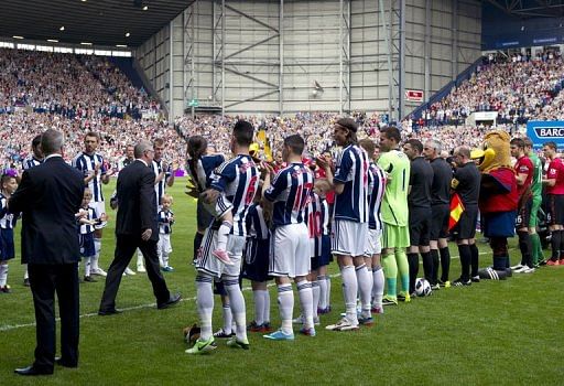 Alex Ferguson (C) is greeted by players in West Bromwich on May 19, 2013