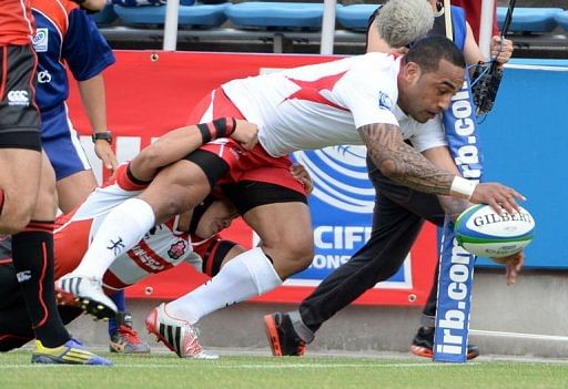 Tonga&#039;s Fetuu Vainikolo (centre) dives to score a try against Japan in Yokohama, May 25, 2013