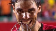 Rafael Nadal does his customary ritual of biting the trophy after his Rio Open win