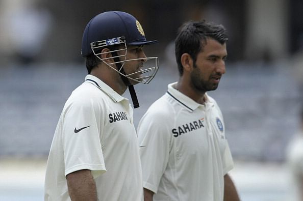 Indian cricket team captain Mahendra Singh Dhoni (L) and Cheteshwar Pujara  walk off the pitch during the second day of the first Test cricket match between India and New Zealand at the Rajiv Gandhi International cricket stadium in Hyderabad on August 24, 2012. AFP PHOTO / Noah SEELAM        (Photo credit should read NOAH SEELAM/AFP/GettyImages)