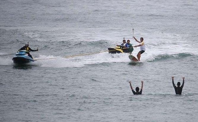 Torch surfs its way into Rio after protests before Games