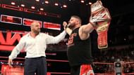 Triple H lifting Kevin Owens's hand after helping him win the WWE Raw Universal Championship