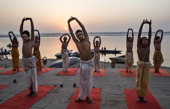 VARANASI, INDIA - APRIL 23:  Young Indian Hindu Brahmins training to be priests perform yoga on a ghat on the Ganges River, holy to Hindus, at sunrise on April 23, 2014 in Varanasi, India.  (Photo by Kevin Frayer/Getty Images)