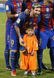 DOHA, QATAR - DECEMBER 13: Afghan boy Murtaza Amadi poses with Lionel Messi of Barcelona during the Qatar Airways Cup match between FC Barcelona and Al-Ahli Saudi FC on December 13, 2016 in Doha, Qatar. (Photo by AK BijuRaj/Getty Images)