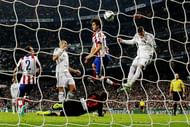 MADRID, SPAIN - JANUARY 15: Sergio Ramos (R) of Real Madrid CF scores their opening goal from a header behind Tiago Mendes of Atletico de Madrid during the Copa del Rey Round of 16 second leg match between Real Madrid CF and Club Atletico de Madrid at Estadio Santiago Bernabeu on January 15, 2015 in Madrid, Spain. (Photo by Gonzalo Arroyo Moreno/Getty Images)