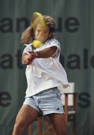 Andre Agassi of the United States wearing his jean style shorts makes a double hand return during a Men's Singles match during the French Open Tennis Championship on 25 May 1988 at the Stade Roland Garros Stadium in Paris, France. ( Photo by Bob Martin/Getty Images)